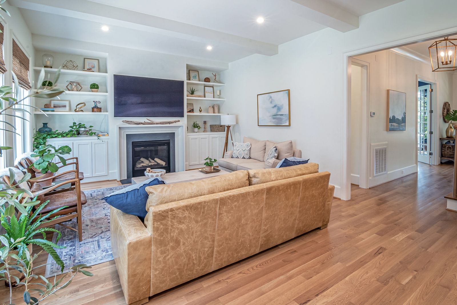 Bright American-style living room with a fireplace, built-in shelves, and warm wood floors